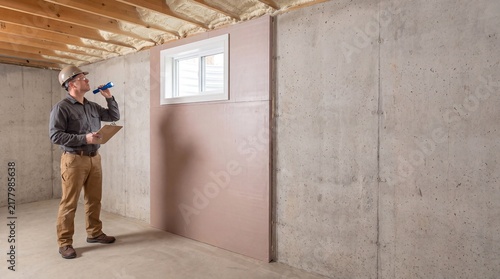 Building Inspector Evaluating Basement Foundation Insulation With Flashlight