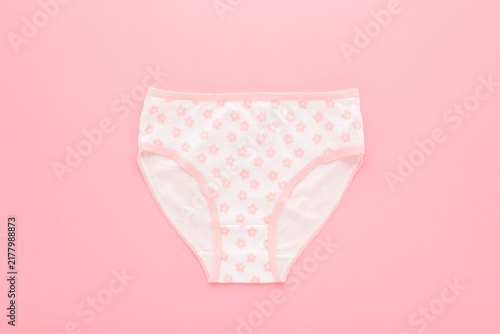 фотографія New white panties with pink flower pattern for little child girl on light pink table background
