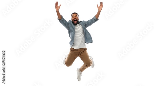 A joyful person doing a small jump with arms raised, smiling brightly. Isolated on white background.