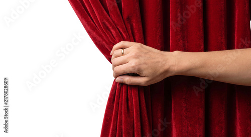 Фотография Hand pulling open a rich red velvet theater curtain to reveal a stage