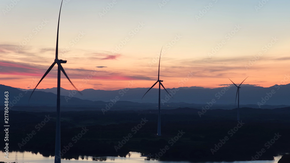 Obraz premium wind turbines silhouette against colorful sunset sky
