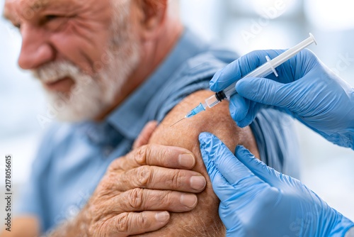 Close-up of medical worker vaccinating older man in arm with syringe in clinic, healthcare support for retired citizens, flu virus protection campaign and coronavirus prevention safety