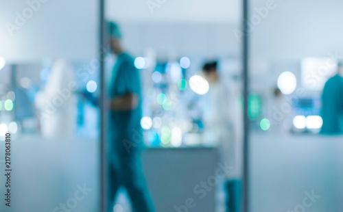 A blurred view of healthcare professionals working in a modern medical facility. The image depicts a vibrant environment with high-tech equipment and collaboration.