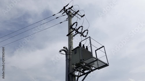 Electrical utility pole with transformer and wires against a cloudy sky.  