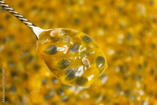 Overhead view of spoonful of ripe passionfruit pulp isolated over textured pulp backdrop