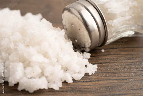 Fotografie Sodium chloride sea salt with salt shaker.