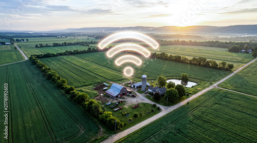 Luminous wifi signal icon hovering over green farm landscape represents smart agriculture and rural connectivity tech.