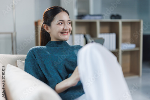 Фотография Young woman relaxing on sofa, smiling, and feeling happy