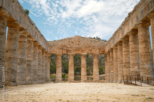 Wide interior perspective view of open courtyard flanked by Doric colonnades leading to end pediment in Segesta, Sicily, Italy