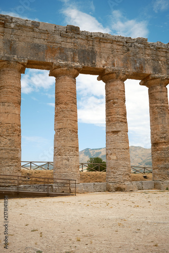 Vertical view of ancient Greek Doric columns supporting stone entablature with distant hills in Segesta, Sicily, Italy