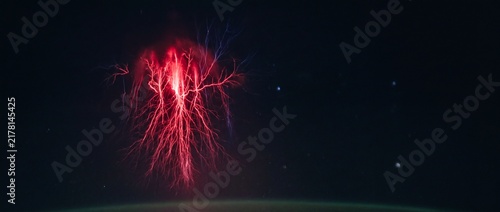 Red sprite upper atmospheric lightning strike displays electrical discharge in dark night sky.
