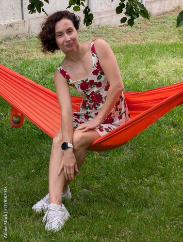Woman Relaxing on Orange Hammock in Garden