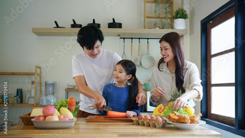 Happy family cooking together in kitchen. Nutrition, healthy food and organic with people teaching and learn to cook at home with bonding