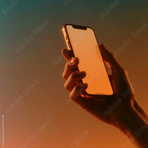 Human Hand Holding Smartphone with Blank Screen in Warm Orange Sunset