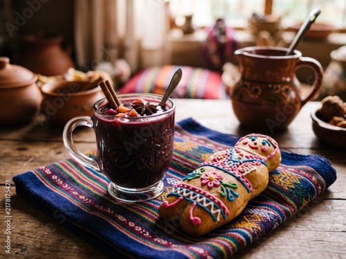 Traditional Ecuadorian Colada Morada drink served with a decorative bread doll on a vibrant Andean textile mat in a rustic kitchen