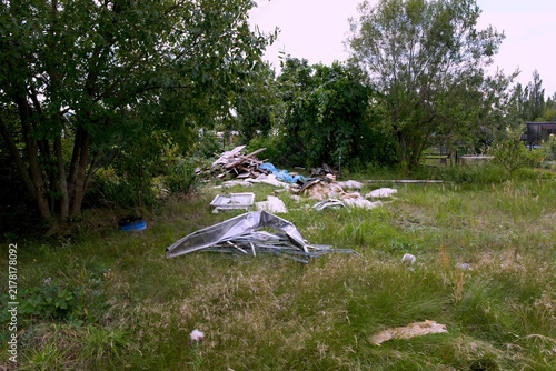 Принти на полотні Construction debris and discarded building materials scattered across an overgrown garden, showing waste, neglect and environmental pollution