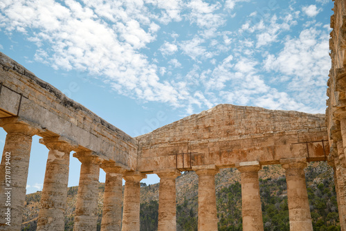 Low-angle interior view showing corner colonnade meeting end pediment under bright cloudy sky in Segesta, Sicily, Italy