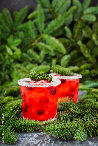 Red christmas cocktail with cranberry juice on the fir branches background. Christmas mood. Selective focus. 