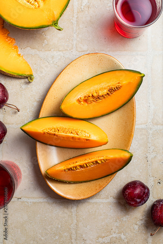 tranches de melon fraîches sur une table, prunes et jus de fruits frais