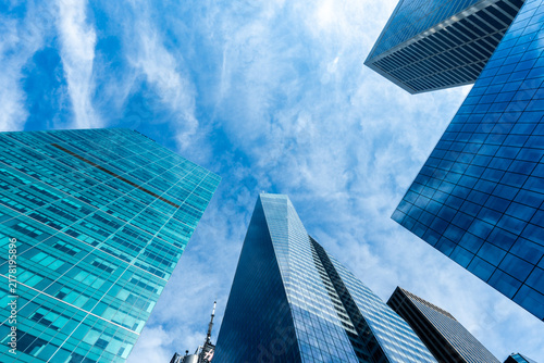 Modern skyscrapers and glass office buildings in business district, captured from low angle perspective with blue sky, symbolizing architecture, urban growth, corporate success, and city development.