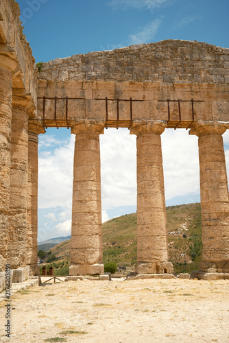 Vertical interior view of Doric colonnade supporting end pediment with mountain view in Segesta, Sicily, Italy