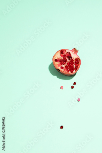 A fresh half pomegranate rests on a green background