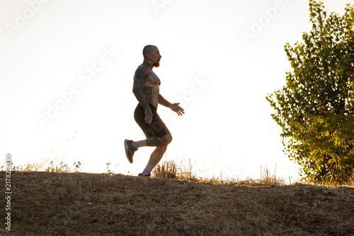 Canvas Print Man runs on a hillside during sunset while wearing shorts and shoes