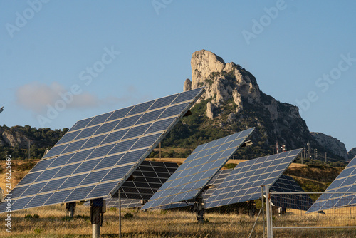Photovoltaic solar tracker panels installation in rural landscape with rocky mountain peak in background