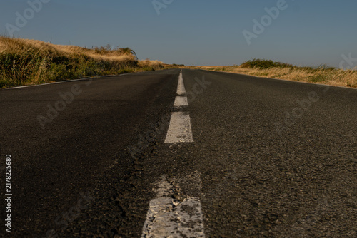 Obraz na płótnie Ground level view of dashed white line on empty country asphalt road in summer d