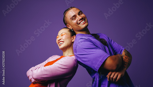 Foto In a smiling studio portrait, friends stand back to back with youthful confidenc