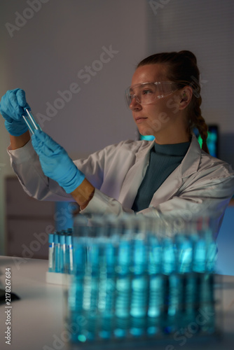 Quadro su tela Female scientist working in a laboratory, carefully examining a test tube with b