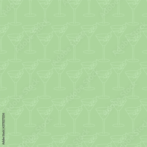 Martini garnished with olives on a skewer, arranged in a zigzag pattern. Green background.