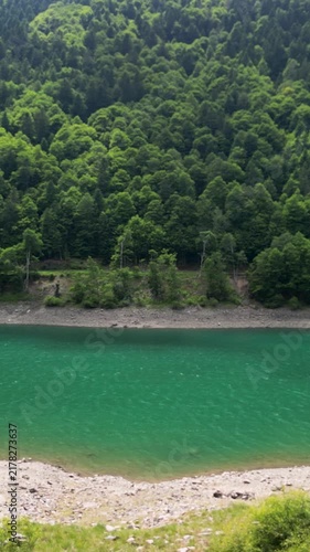 Aerial drone flying above a turquoise river and green forest.Vertical video