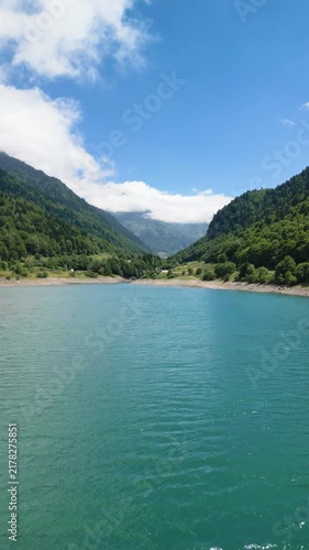 Drone flying over turquoise mountain lake water.Vertical video