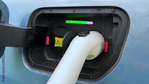 Bild auf Leinwand Charging port on electric vehicle with connected cable and colored indicator lig
