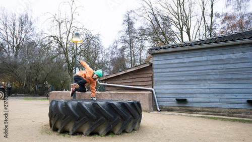 Konstfotografi Young boy vaulting over tire in outdoor park