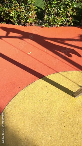 Shadows of children swinging on a playground on a sunny day