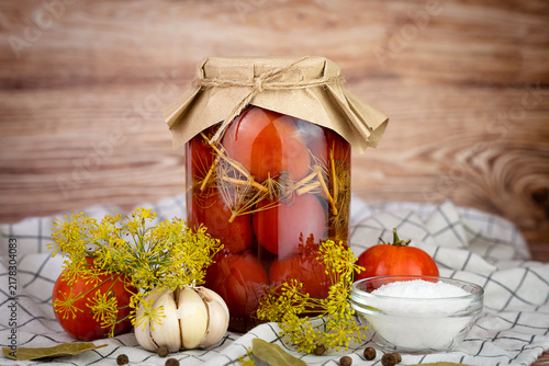 Glass jar of homemade preserved tomato with garlic, dill and spices. Traditional preparations for winter. Close-up. Copy space.