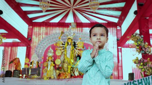Devotional Young Boy Offering Prayer at a Colorful Durga Puja Celebration