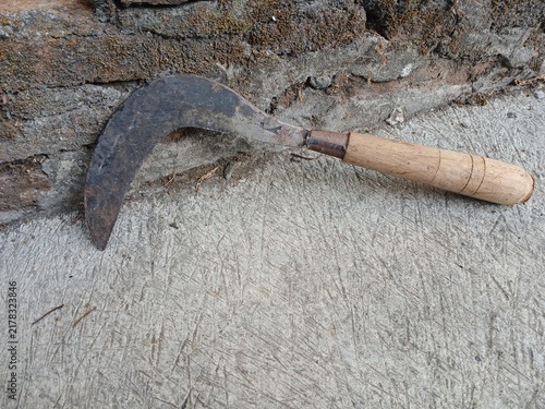 Canvastavla Traditional rusty sickle with wooden handle placed on concrete surface near bric