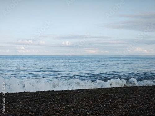 Canvas Print Blue sea with a crashing wave on a pebble beach