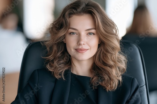 Portrait of a confident young businesswoman sitting in an office chair smiling