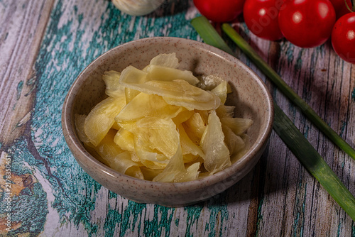 Canvastavla Pickled ginger in a ceramic bowl with fresh vegetables on a rustic wooden table