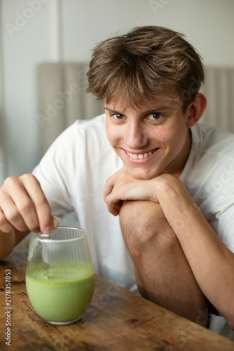 Canvastavla Happy beautiful teenager looking at camera and mixing fresh green matcha latte d