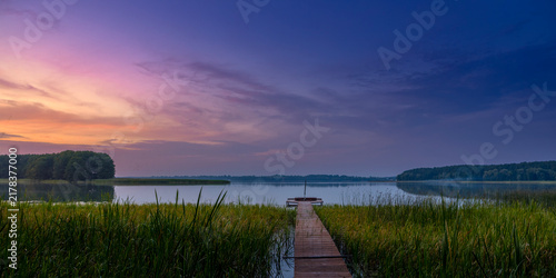Tranquil Sunset Over Lake with Wooden Pier and Reeds Landscape