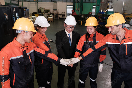 The supervisor and workers joined hands to encourage each other before starting work in the factory.
