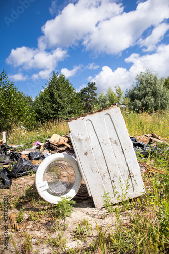 Ecological problem. Household waste in nature. Consequences of human activity.  Beautiful cloudy sky and old broken washing machine.
