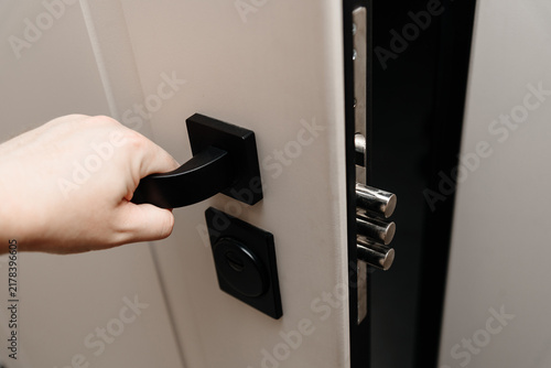 modern metal door to apartment, lock in three rods form, door slightly open, man hand on handle, coming home concept