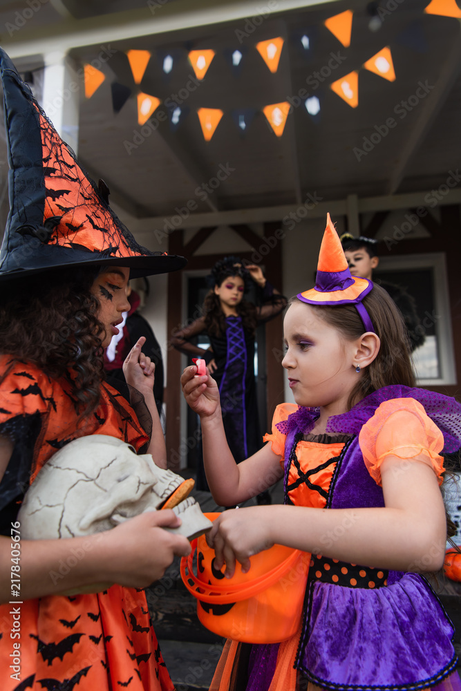 Fototapeta premium Cute little children joyfully dressed in Halloween costumes enjoying trick or treat fun