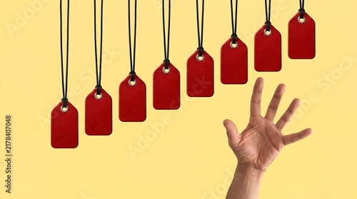 Hand reaching for rising red price tags on yellow background